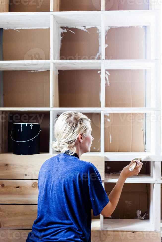Woman Applying the First layer of Paint on a Wooden Library photo