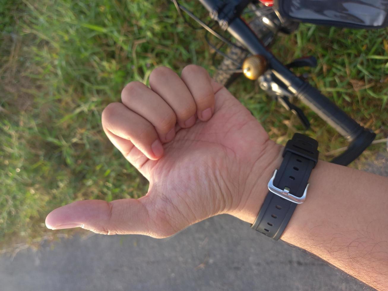 Man left hand showing thumb on grass park photo