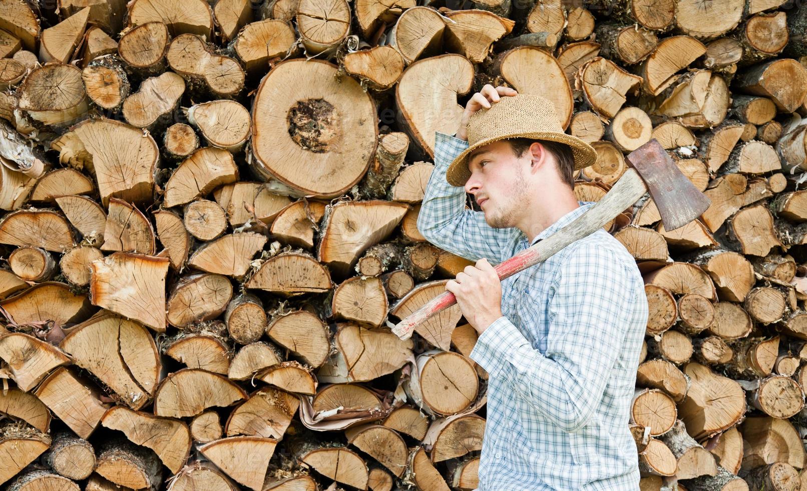 Woodcutter with straw hat on a background of wood photo