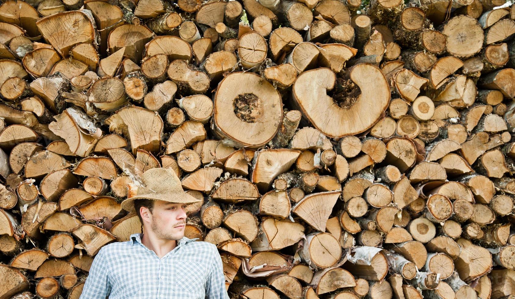 Woodcutter with straw hat on a background of wood photo