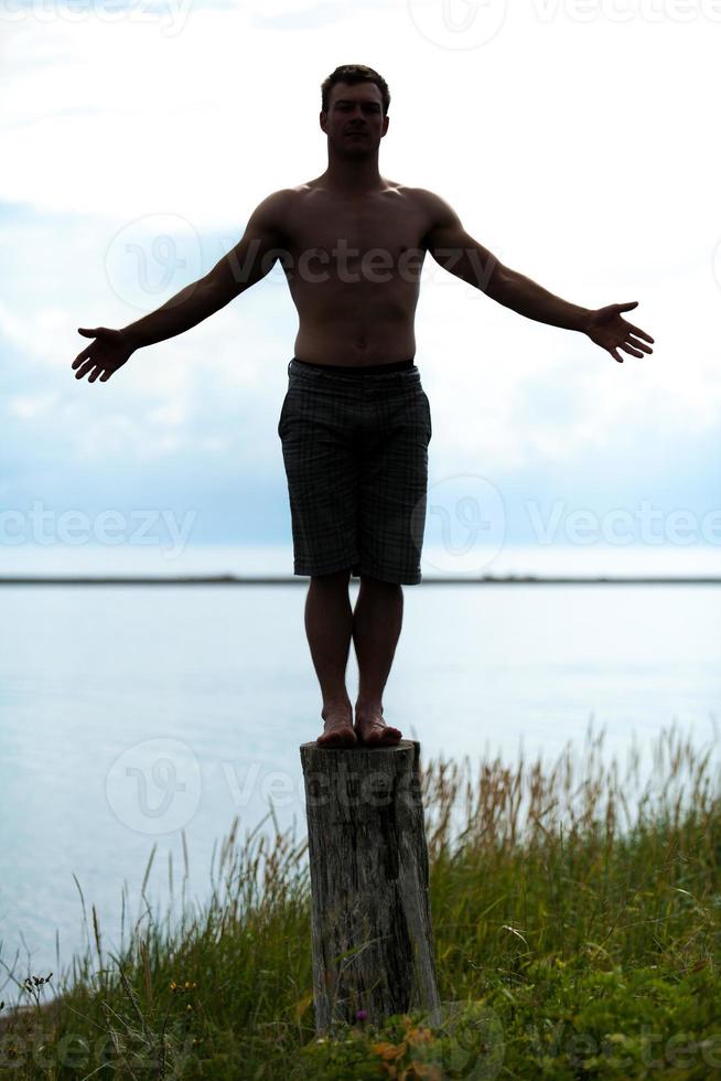 silueta de hombre haciendo yoga en un tocón en la naturaleza foto