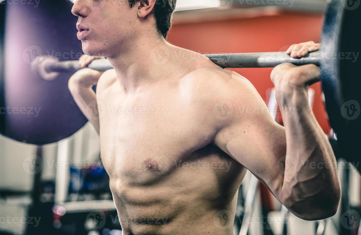 Crop man squatting with barbell photo