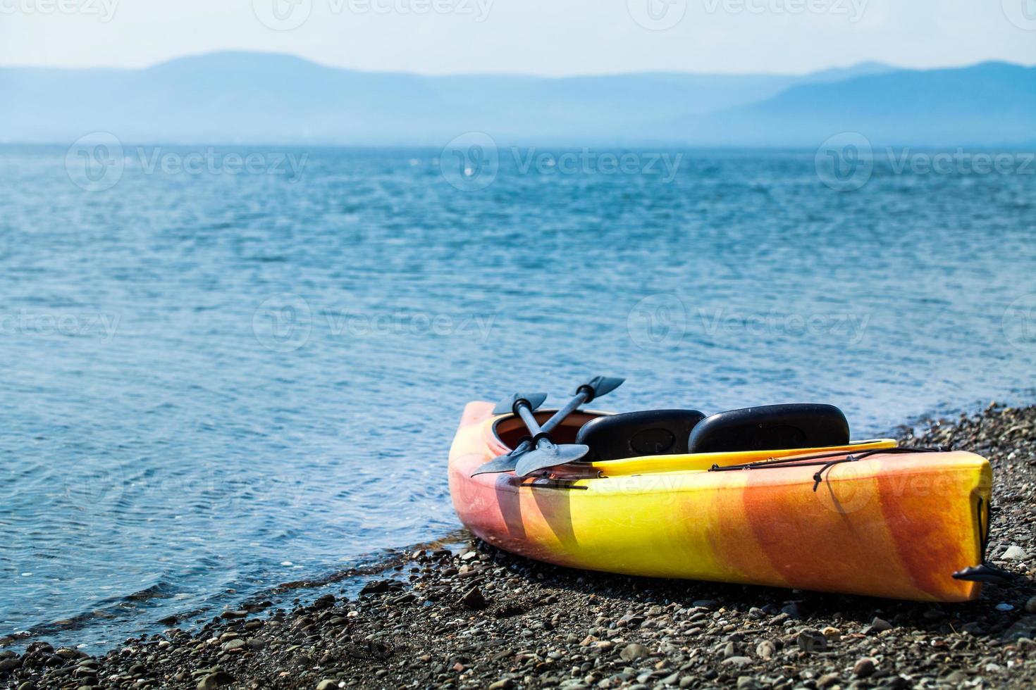 Orange and Yellow Kayak With Oars on the Sea Shore photo