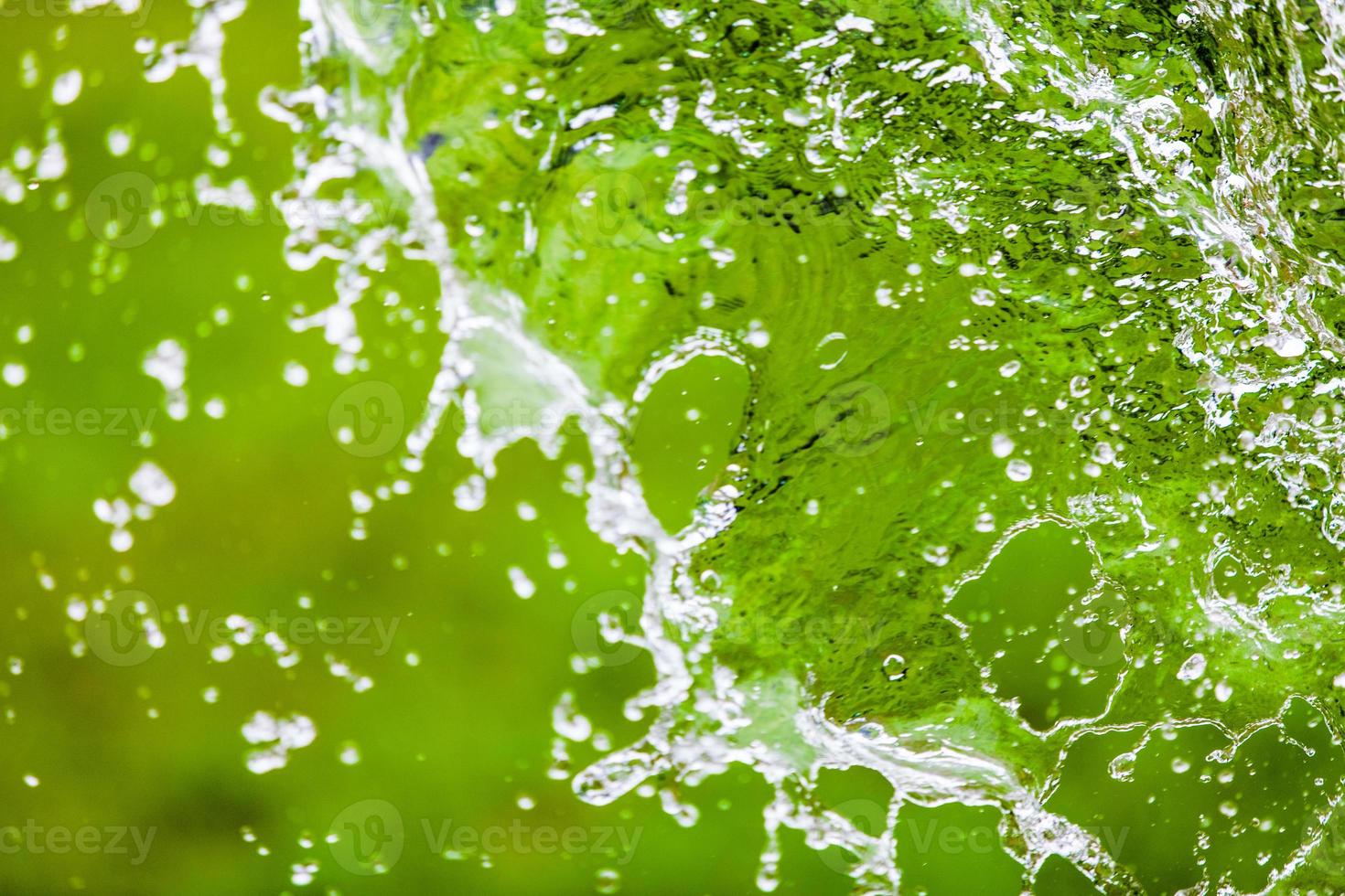 Salpicaduras de agua cayendo sobre fondo abstracto verde con espacio para texto foto