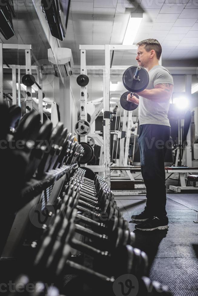 Bodybuilder lifting barbell in gym. photo