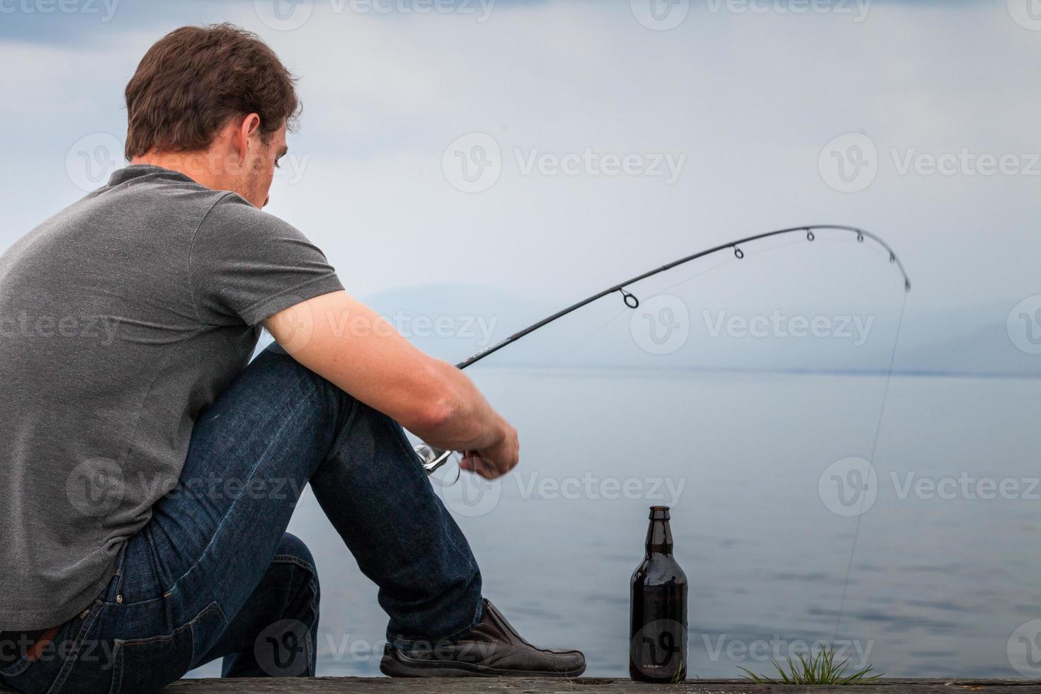 Young Fisherman Fishing Mackerel sat on the Dock photo