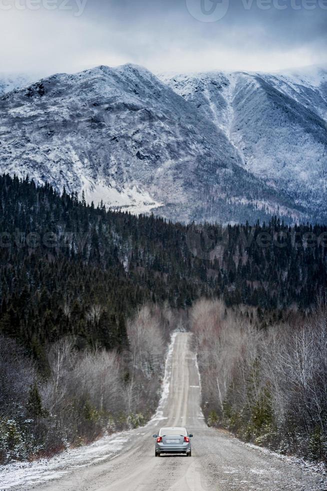 Carretera recta de invierno con hermosas montañas nevadas en segundo plano. foto