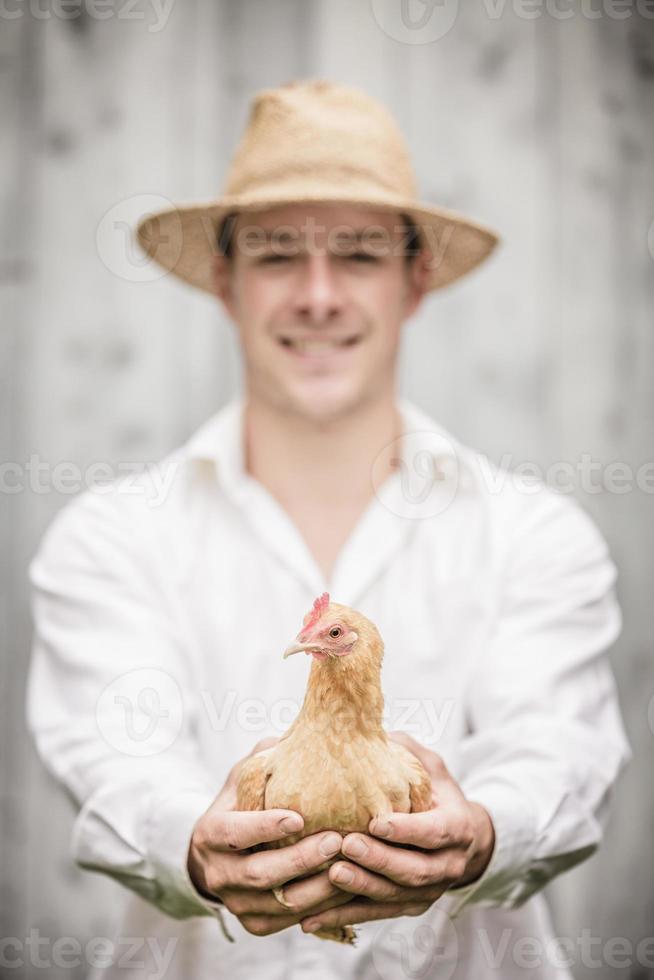 granjero sosteniendo un pollo beige foto