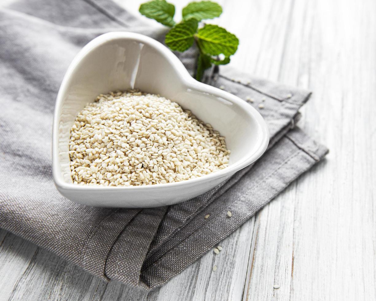Sesame seeds in a bowl  on a rustic table photo