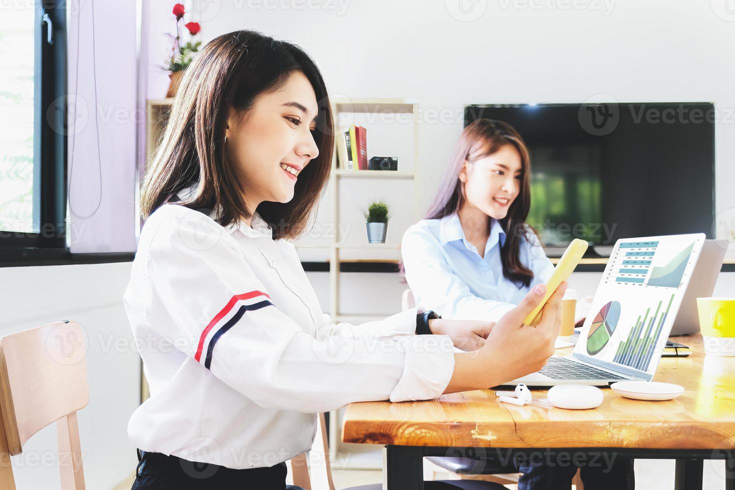 A female employee uses a phone and computer to check the company's investment budget. photo