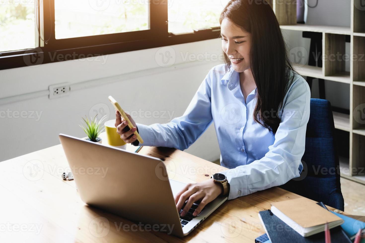 concepto independiente, mano femenina que sostiene el teléfono inteligente y las computadoras para diseñar el trabajo según lo ordenado por los clientes foto