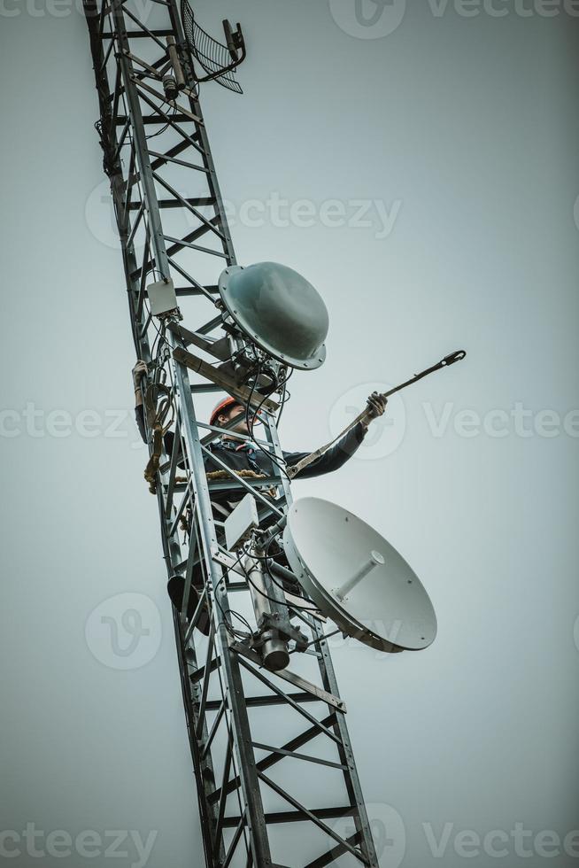 Trabajador de telecomunicaciones recortando el arnés del mosquetón por seguridad foto