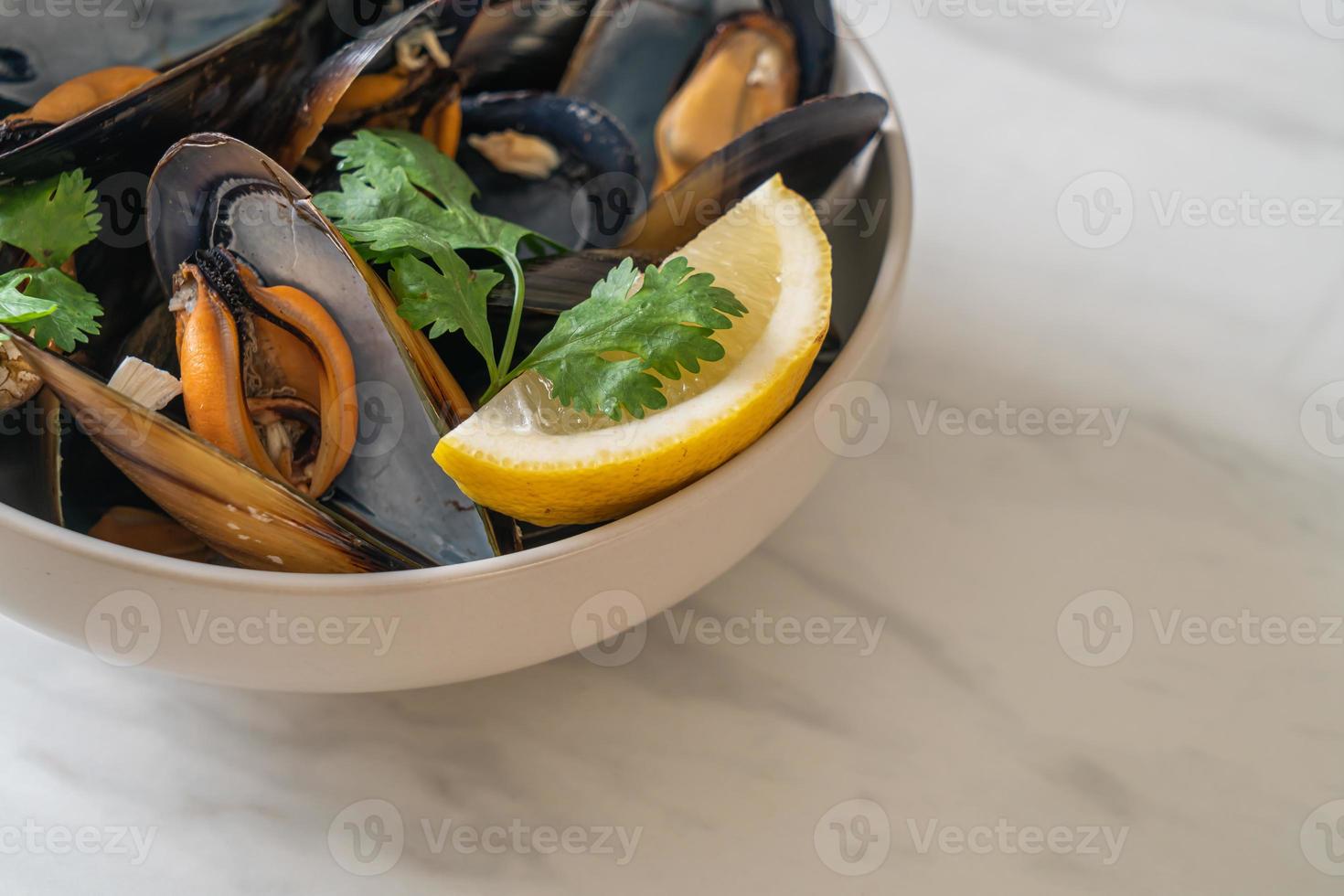 mejillones con hierbas en un bol con limón foto