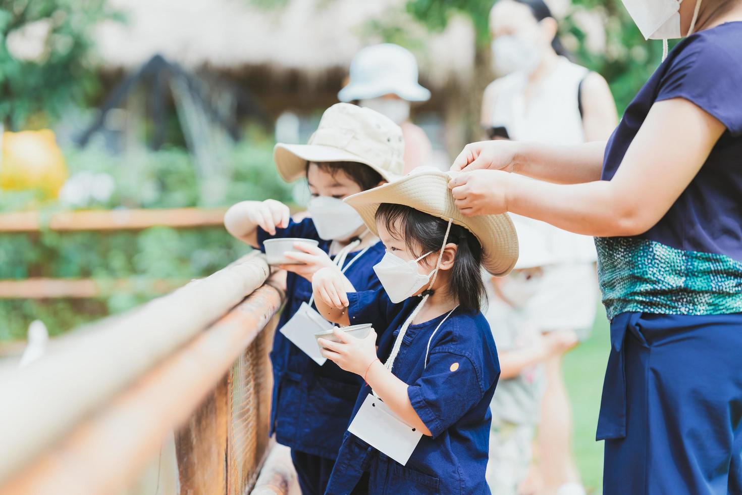 una madre está abrochando el sombrero de su hija para ventilarlo. mamá se encarga de la ropa de los niños mientras los niños hacen divertidas actividades de levantamiento de animales. foto