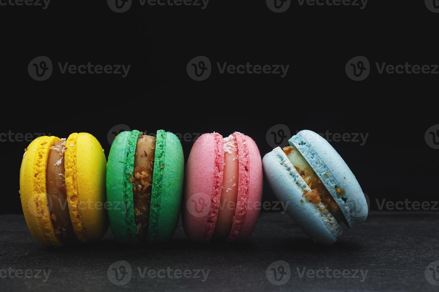 four multi-colored homemade natural products macaroon on a black background photo