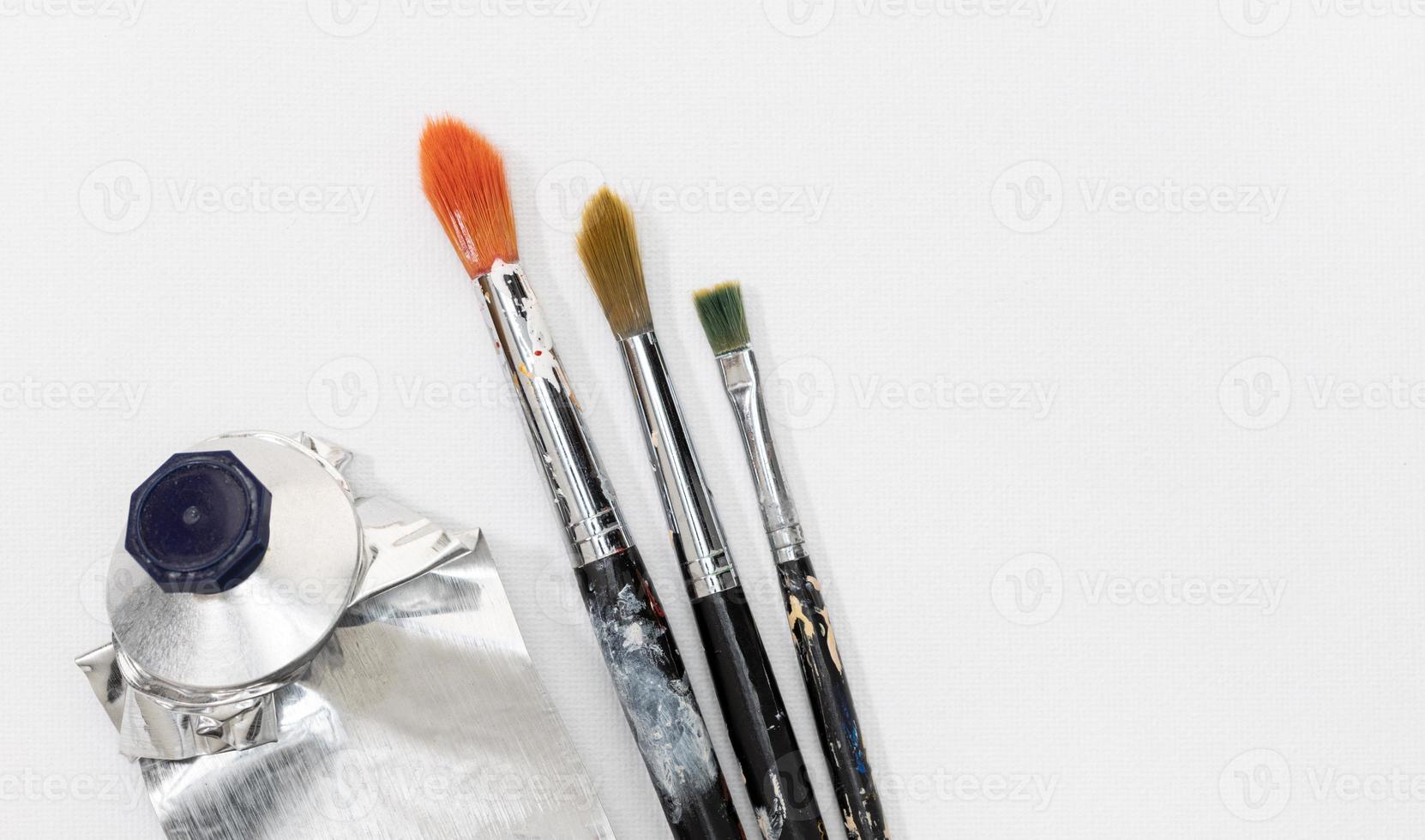 Paintbrushes and squeeze oil paint tube on white canvas background. Copy space photo