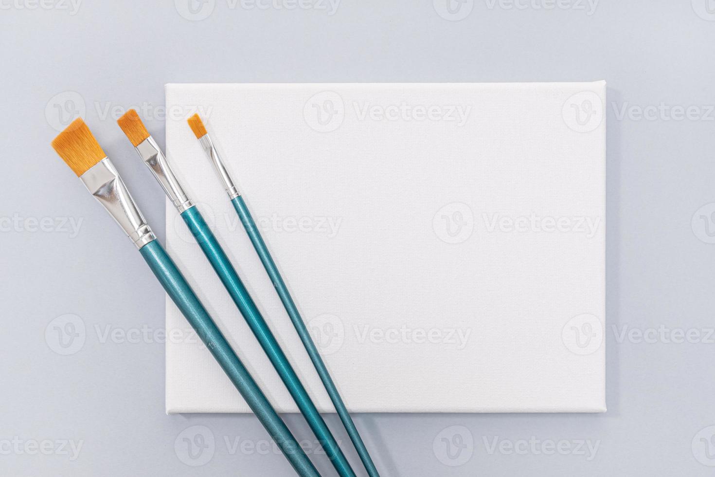 Blank White canvas and paint brushes isolated on gray background. Template, mock up photo
