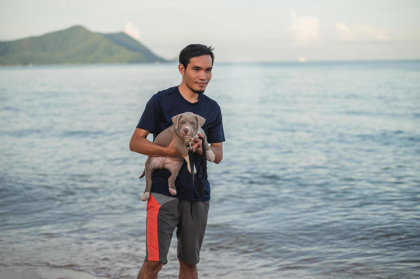 hombre y perro viajan en la playa del mar foto