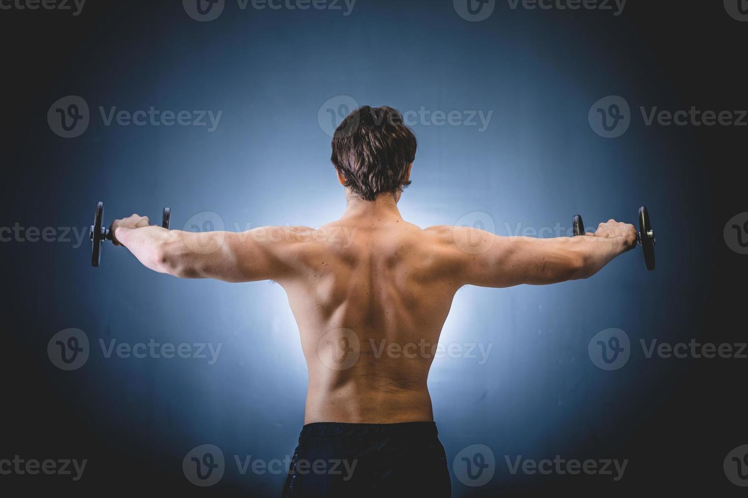 Muscular man doing shoulders exercise with barbell photo