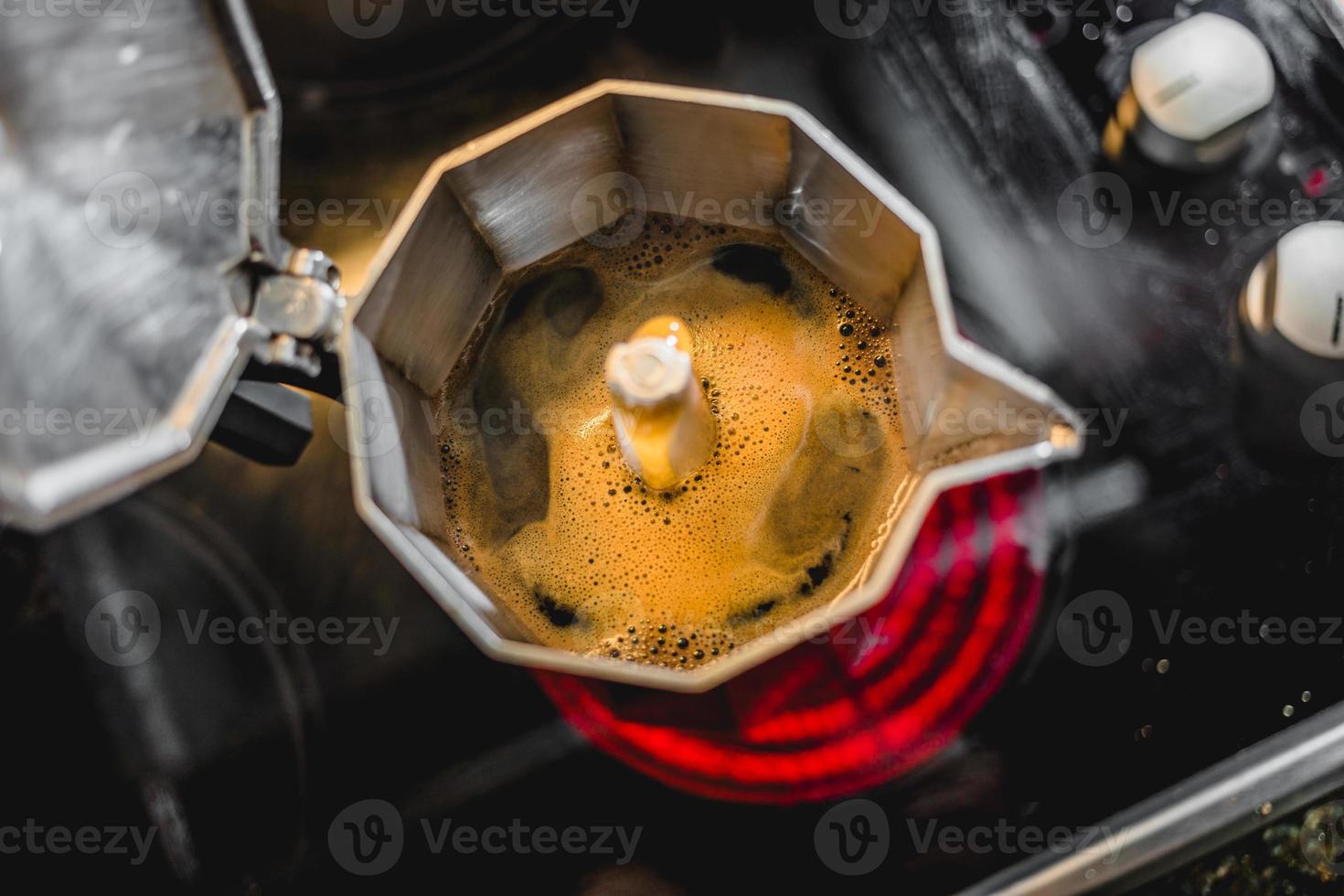 Cafetera italiana de aluminio preparando un café oscuro recién hecho en la estufa foto