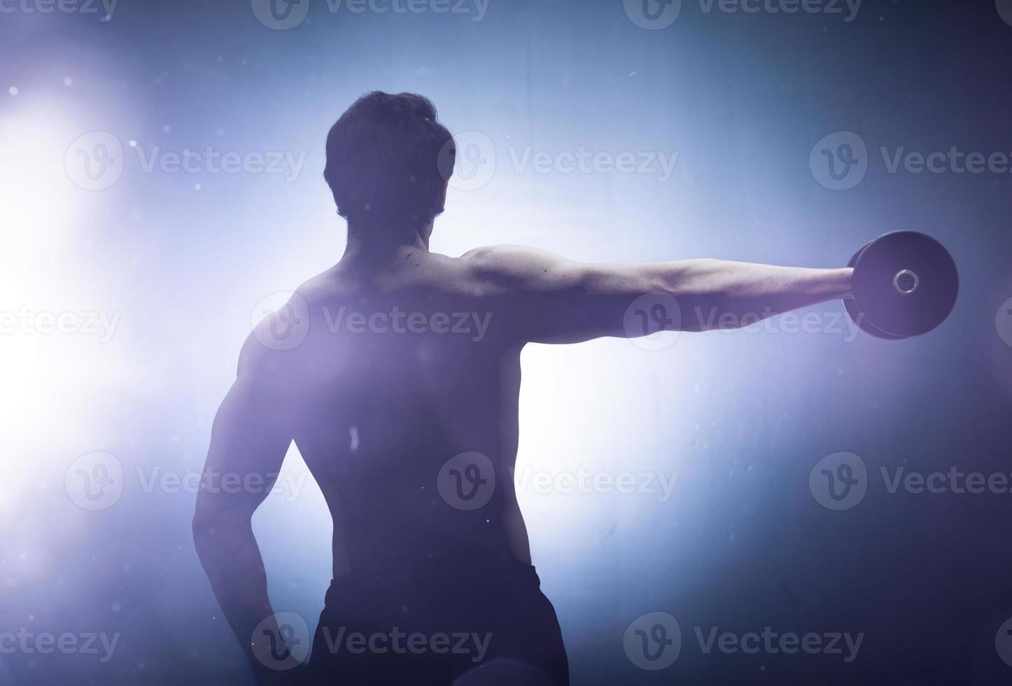 Hombre levantando pesas a un lado en luz brillante foto