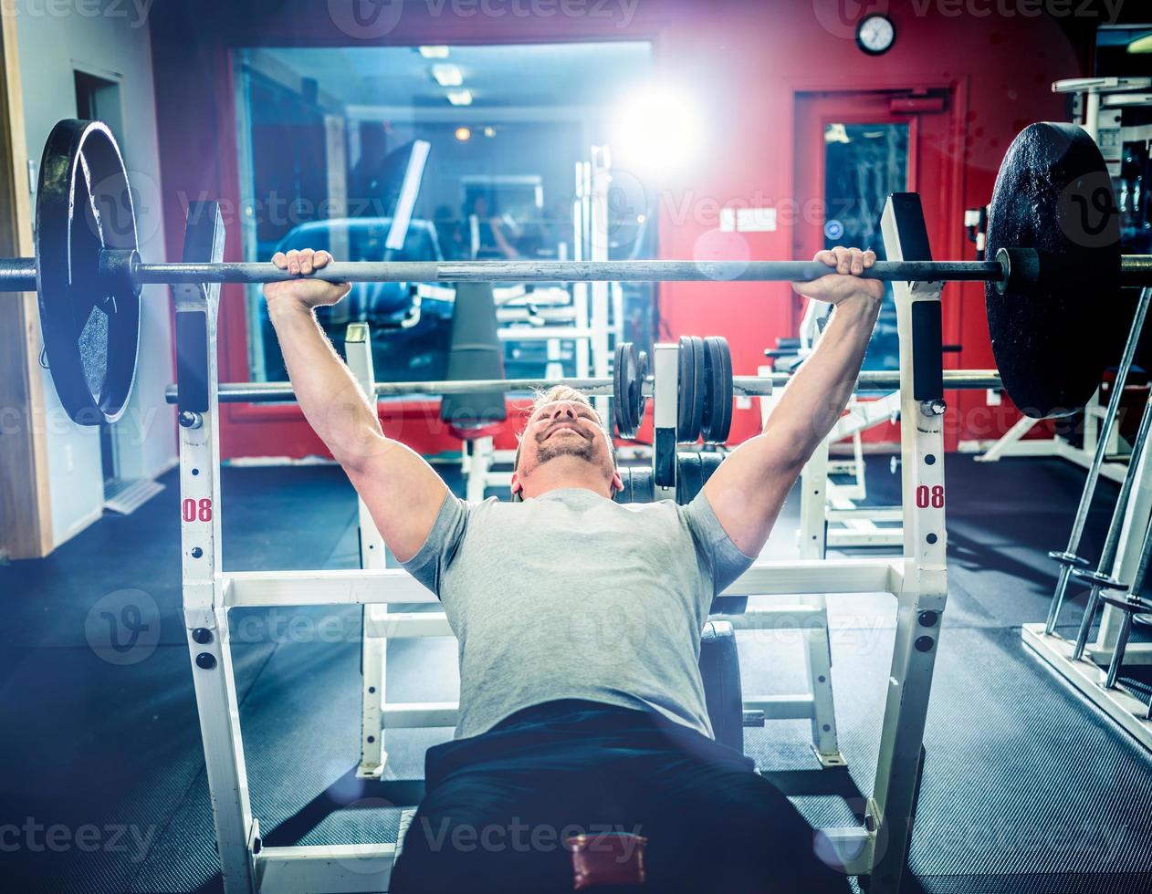 Man doing bench press in gym photo