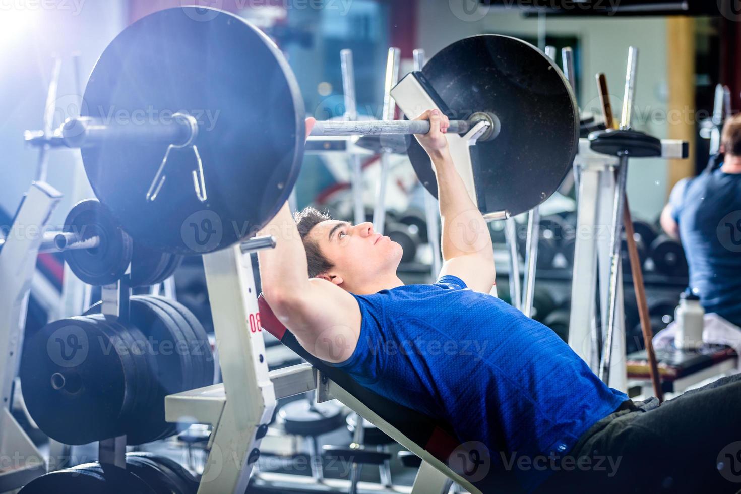 Man pressing barbell on incline bench. photo