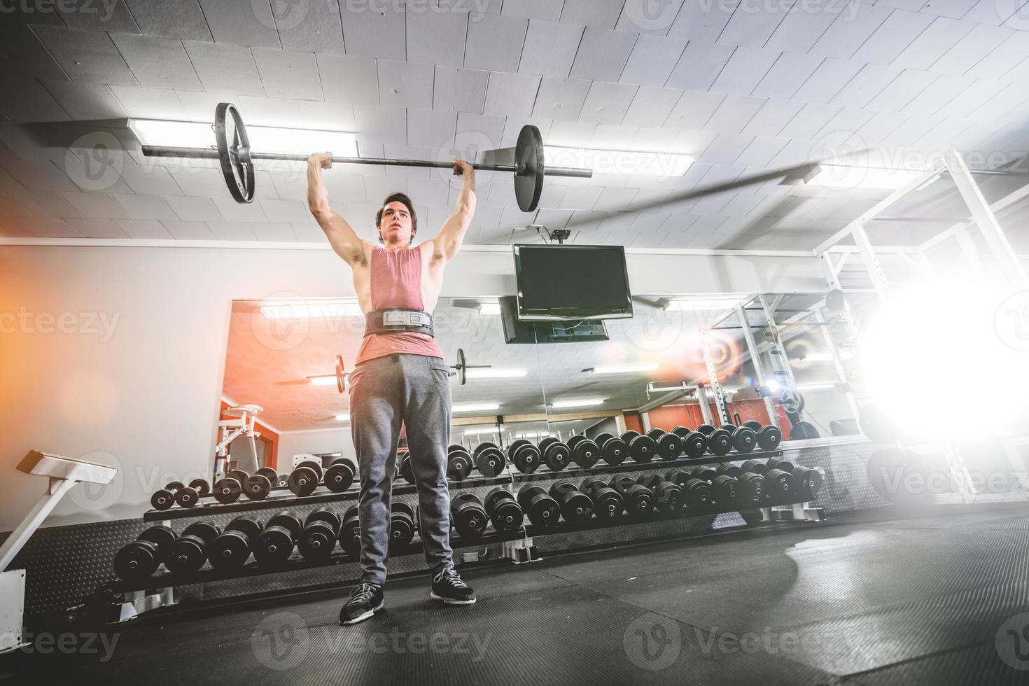 Man lifting barbell above head photo