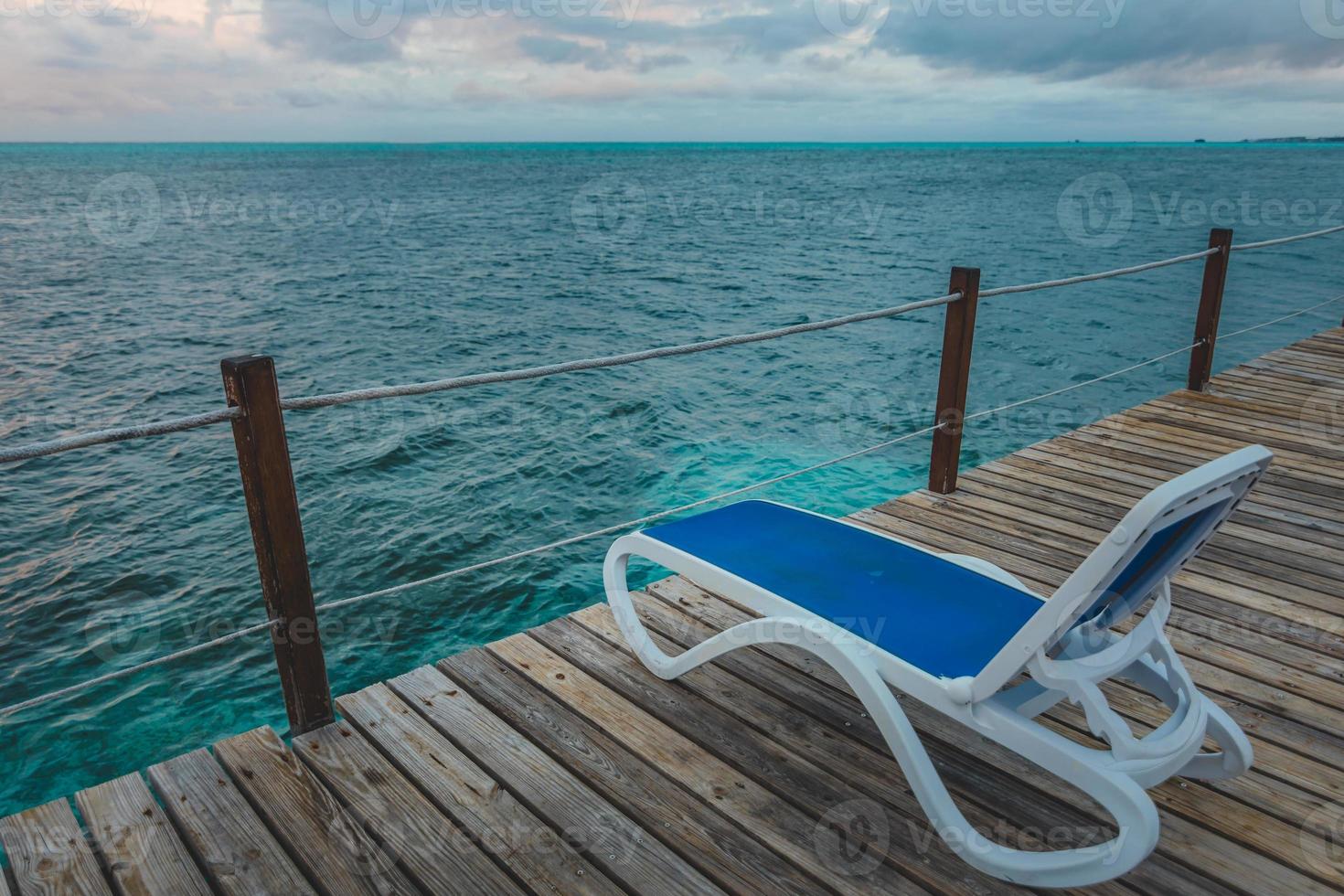 muelle de madera y largas sillas azules sin nadie foto