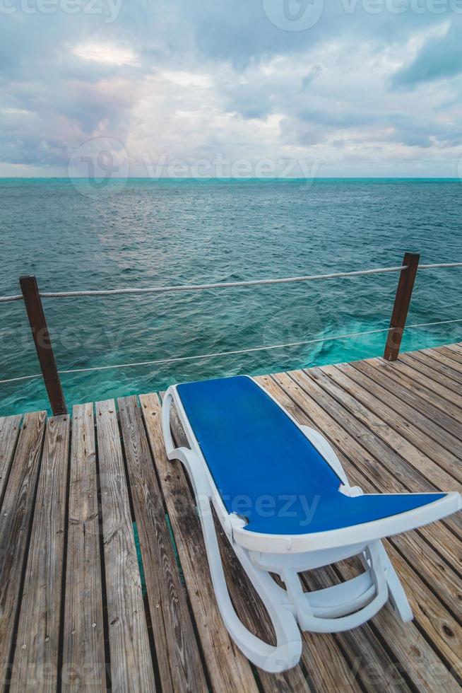 muelle de madera y largas sillas azules sin nadie foto