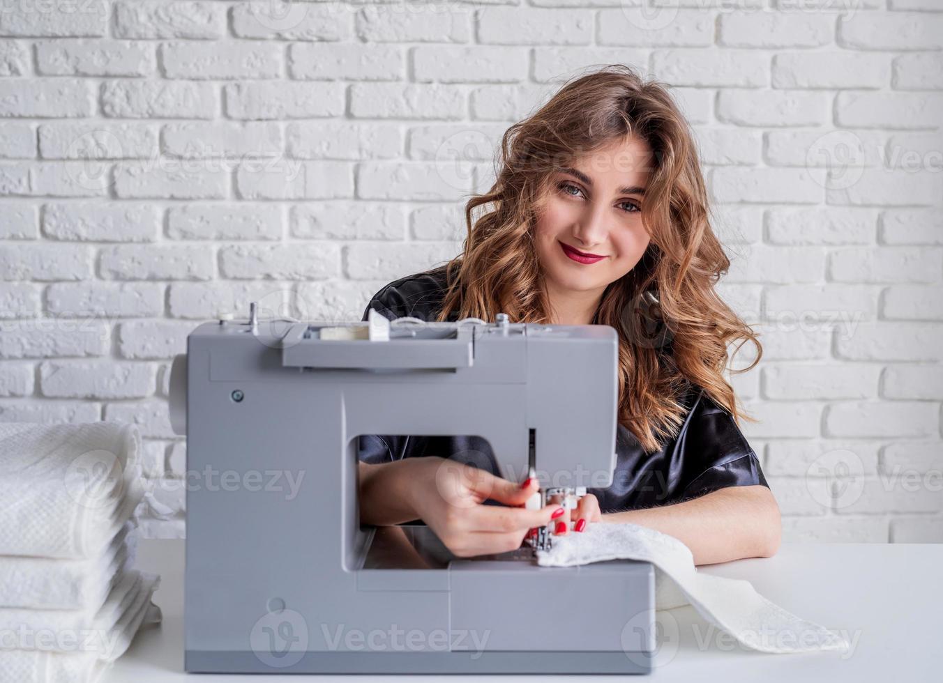 Mujer cosiendo ropa en la máquina de coser en casa foto