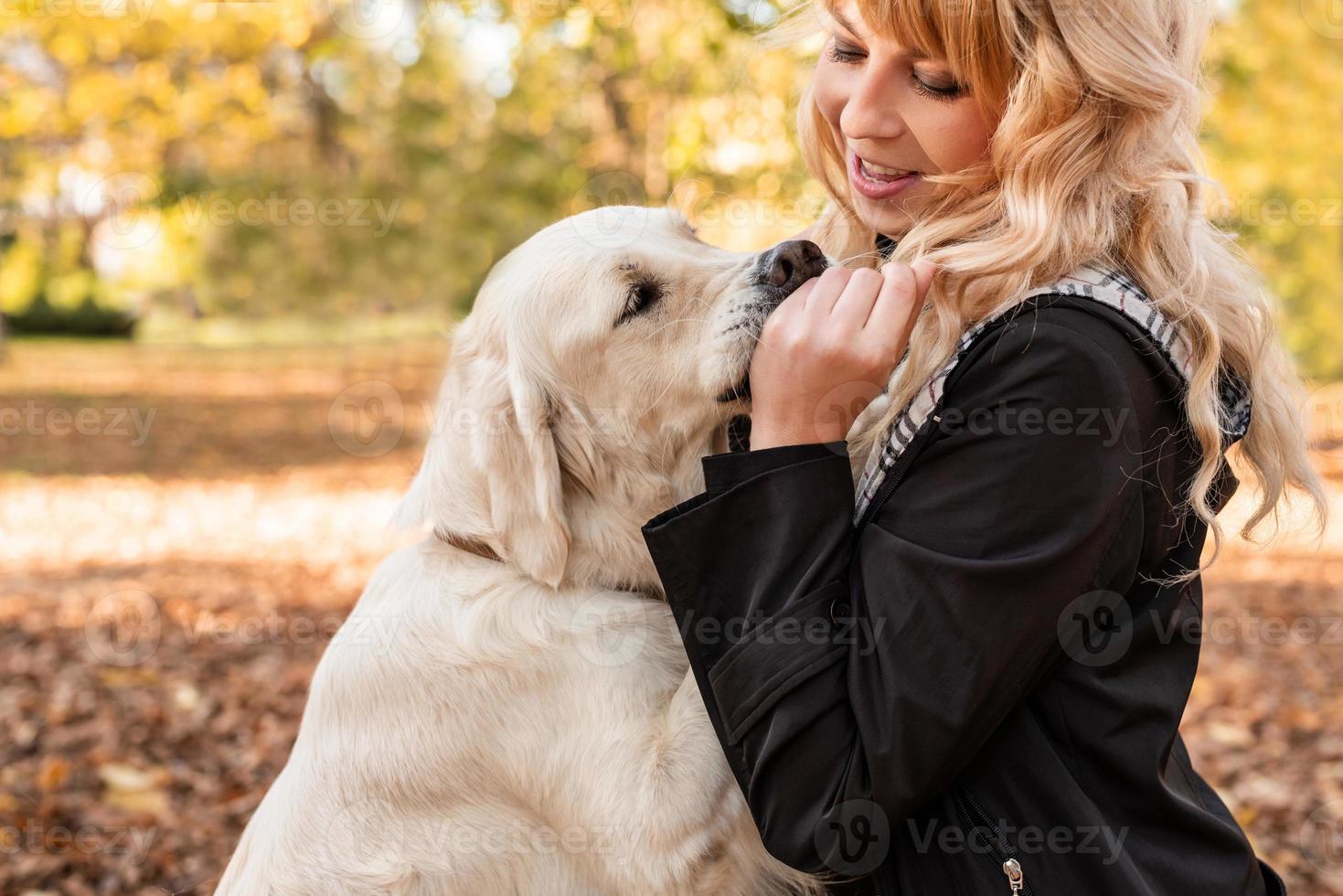 happy owner woman playing with her retriever dog in autumn park photo
