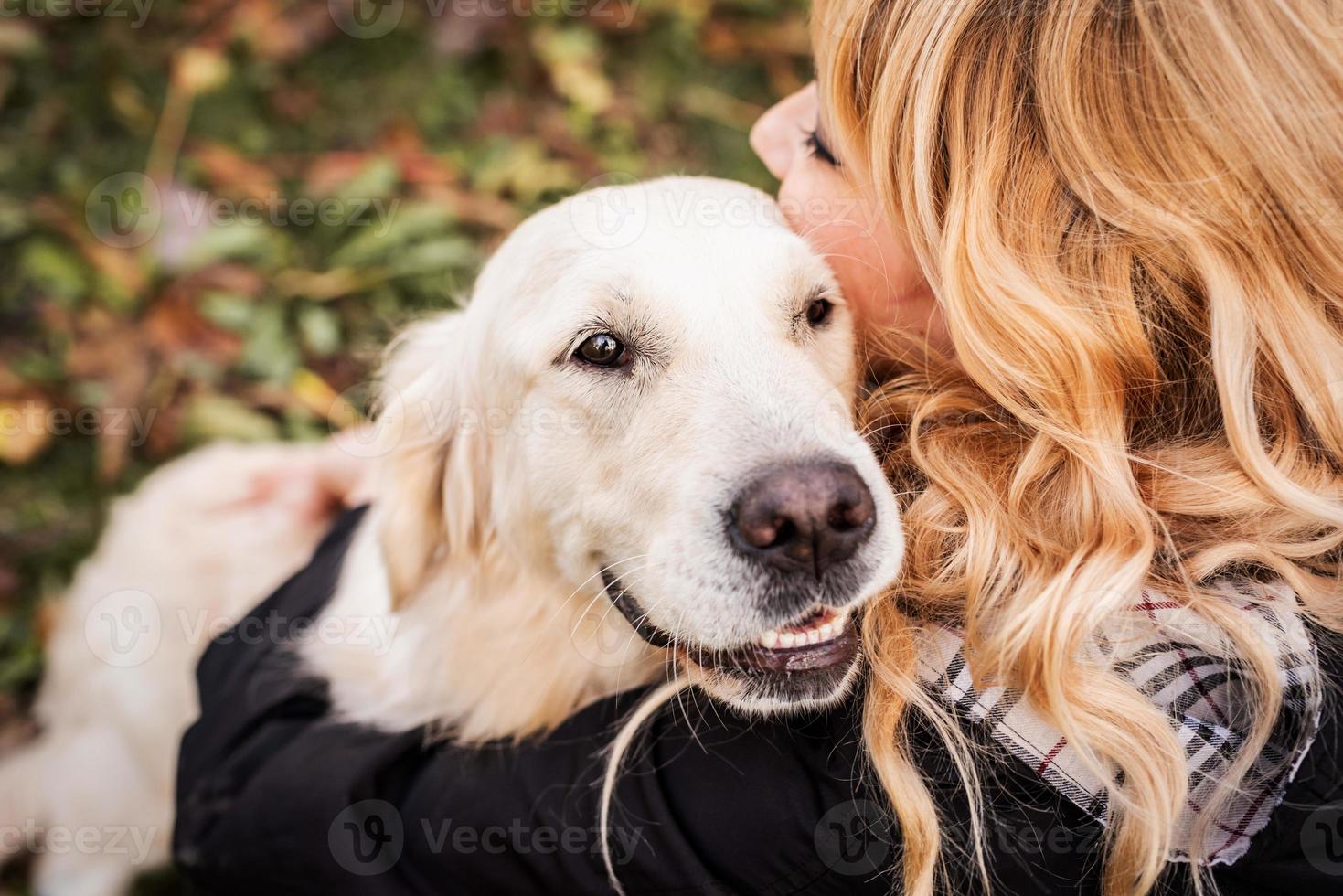 Una mujer rubia abrazando a su perro perdiguero en el parque foto