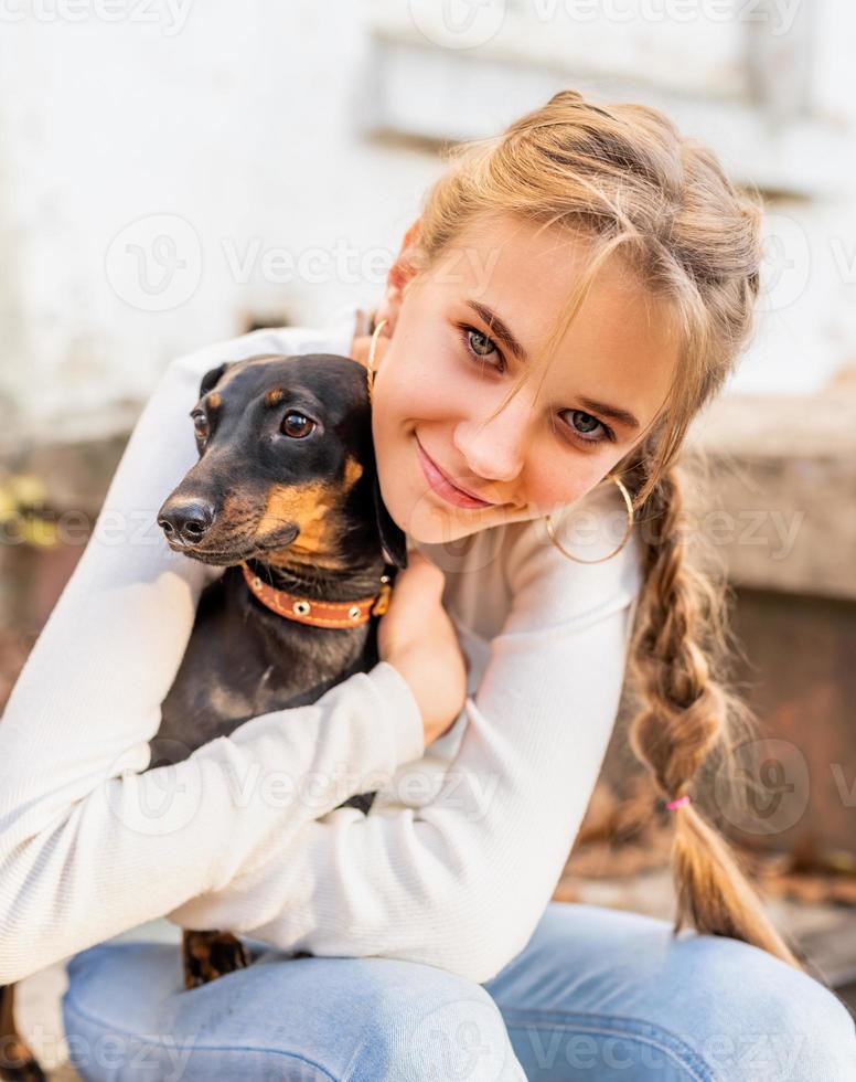 Adolescente abrazando a su perro teckel al aire libre foto