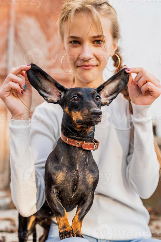 teenager girl playing with her dachshund dog outdoors photo