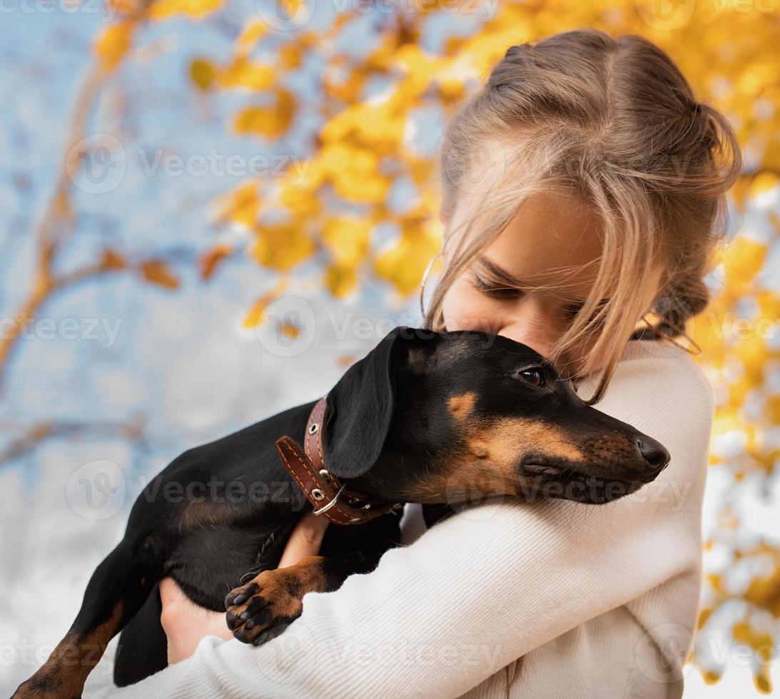 teenager girl hugging her dachshund dog outdoors photo