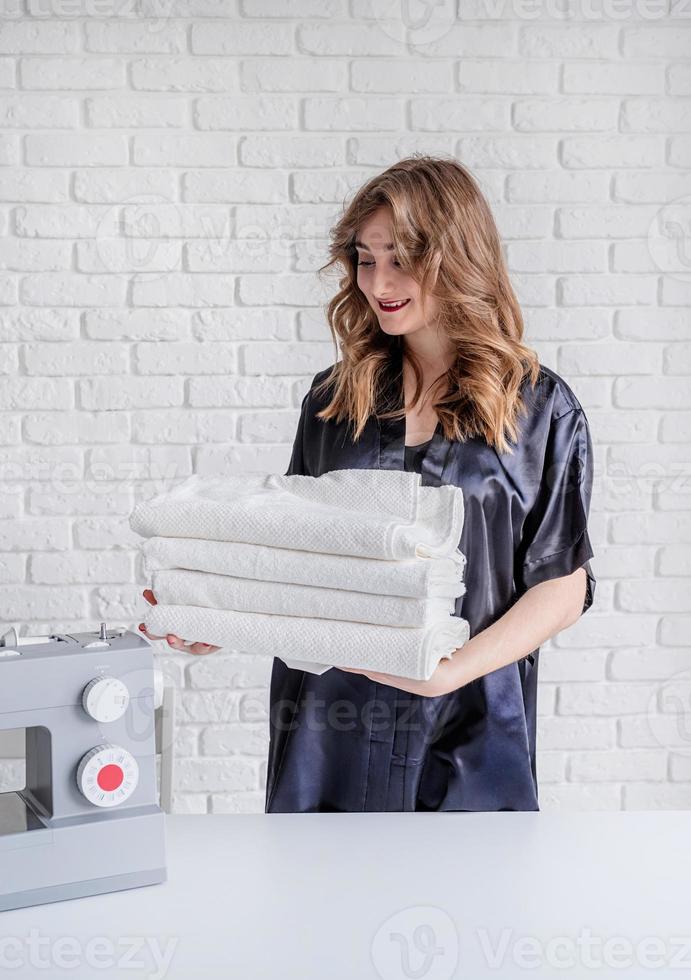 Beautiful woman holding clean white towels at home photo