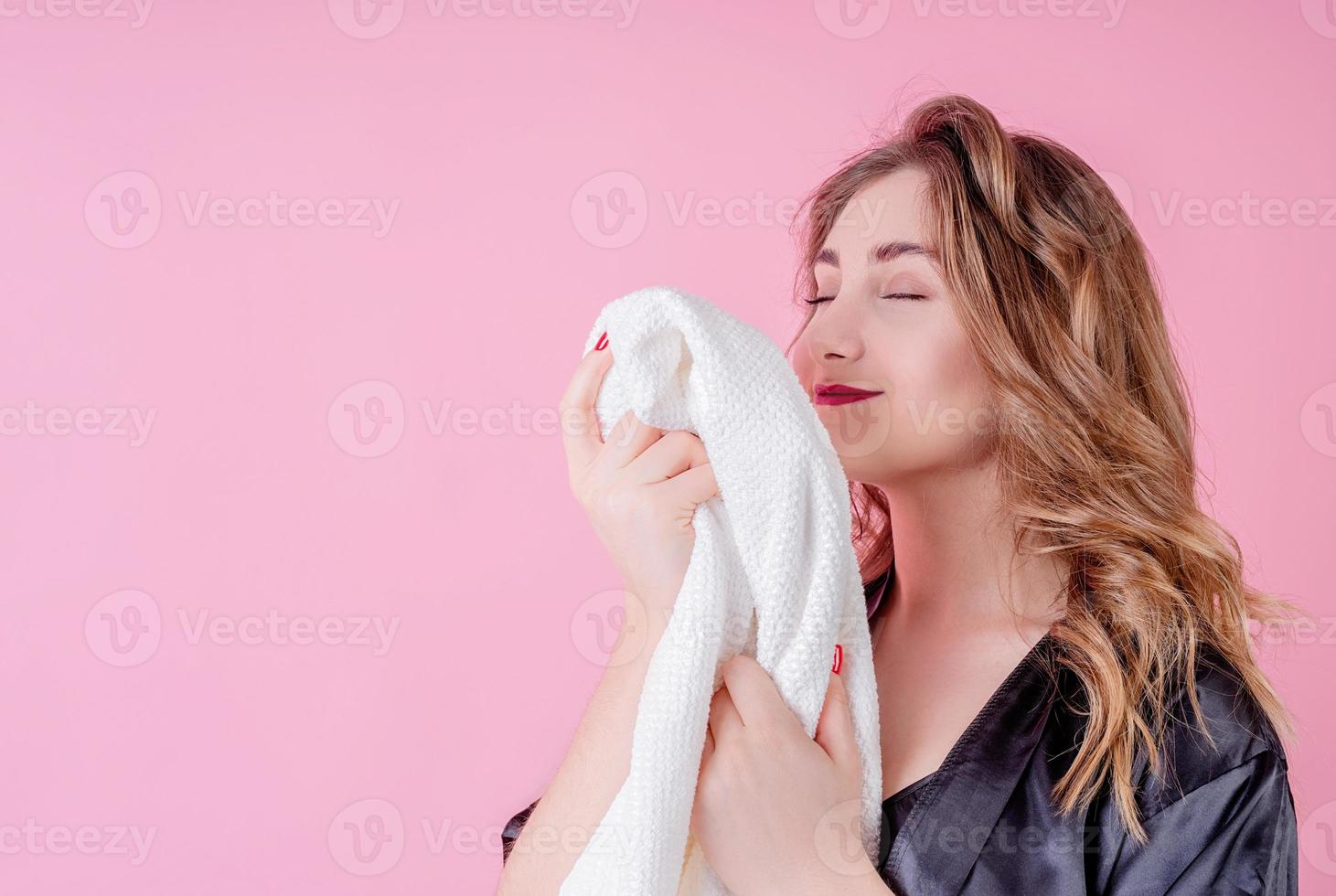 beautiful woman smelling clean clothes isolated on pink background photo