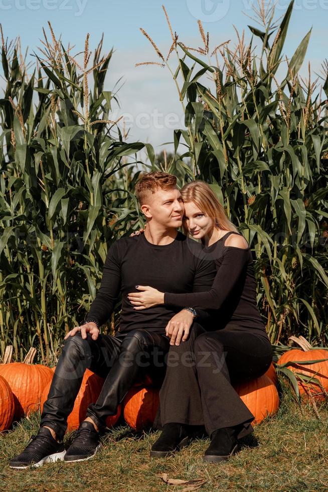 Happy family sitting on hay bales and holding pumpkins at outdoor market. Autumn time. photo