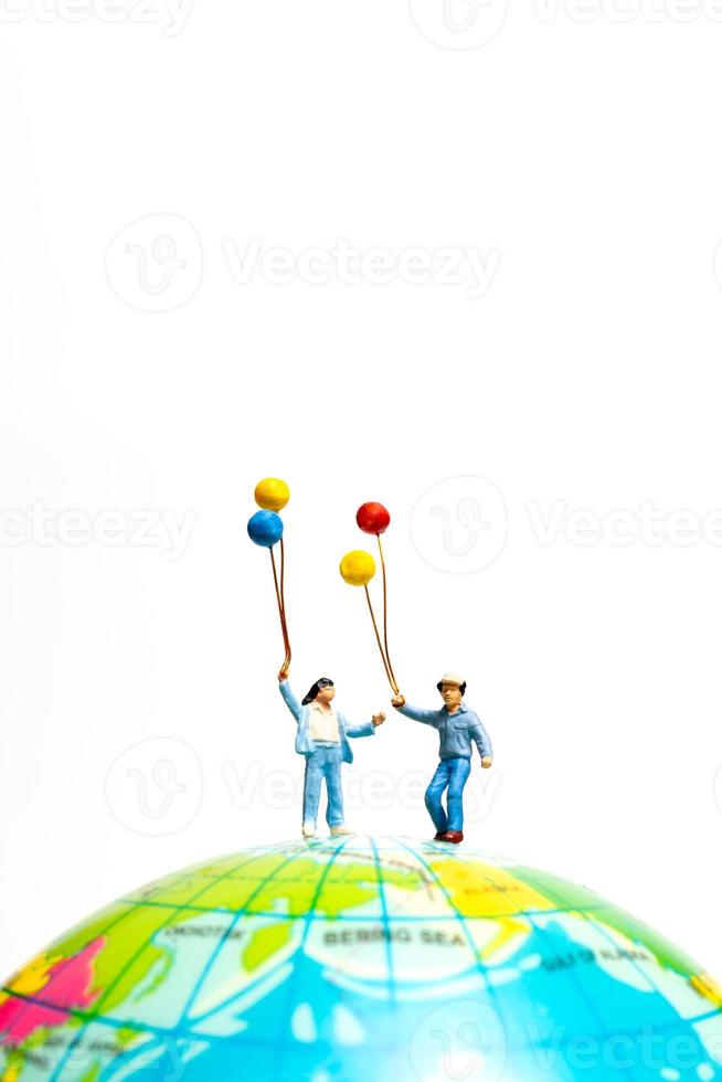 Miniature people , Childrens holding balloons standing on the globe photo