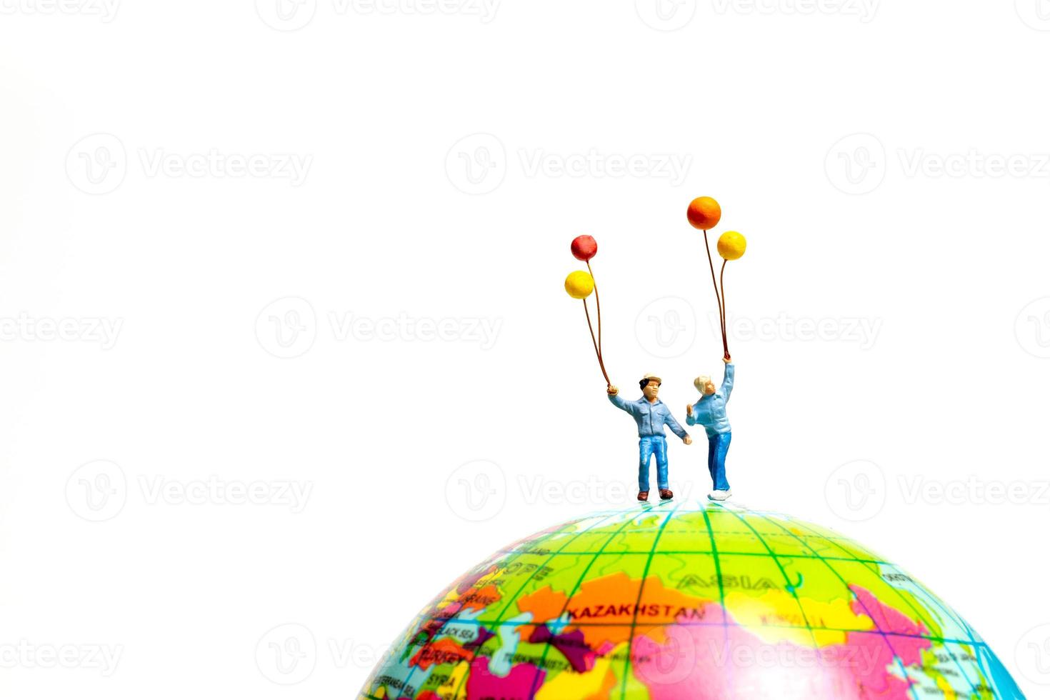 Miniature people , Childrens holding balloons standing on the globe photo