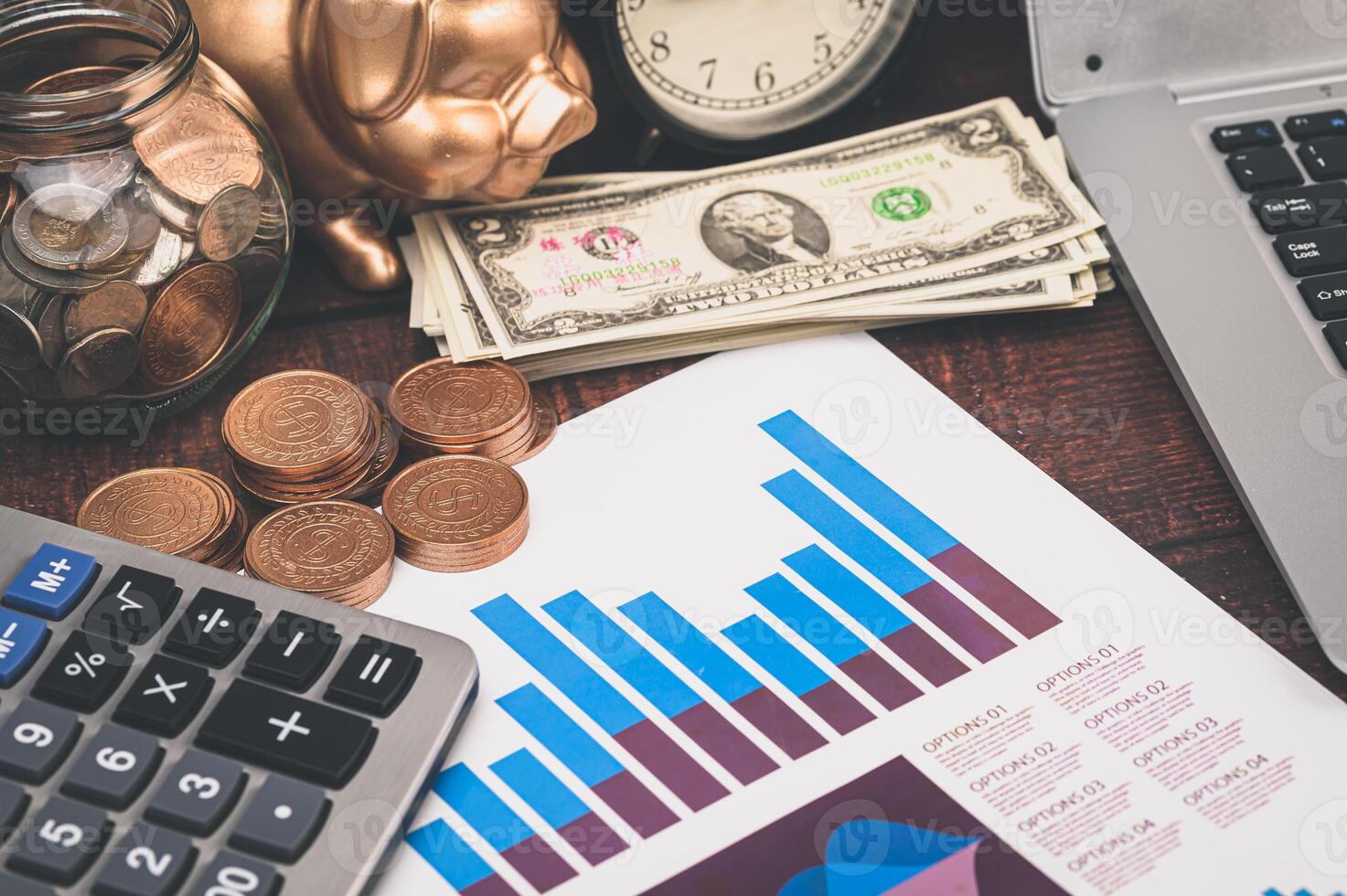 A laptop, calculator, and money are on a desk photo