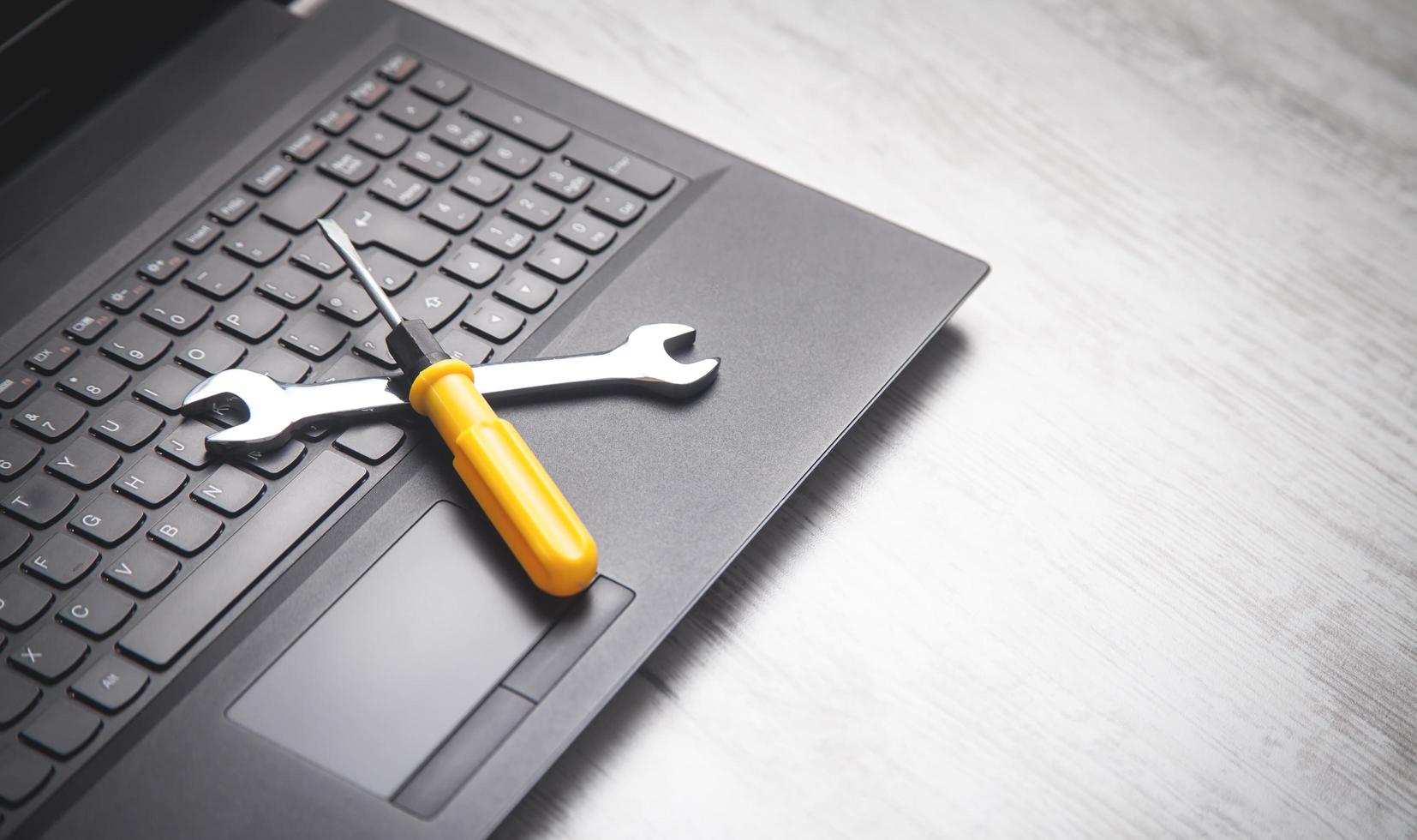 Wrench and screwdriver on the computer keyboard. IT Service. Support photo