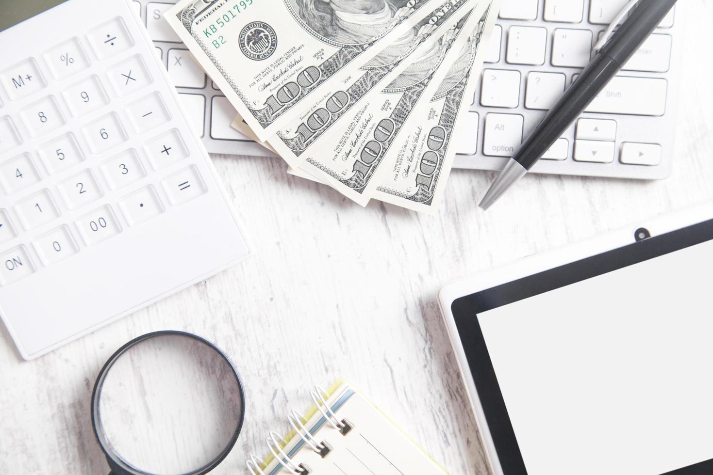 Hundred dollar banknotes with a computer keyboard, tablet and calculator. photo