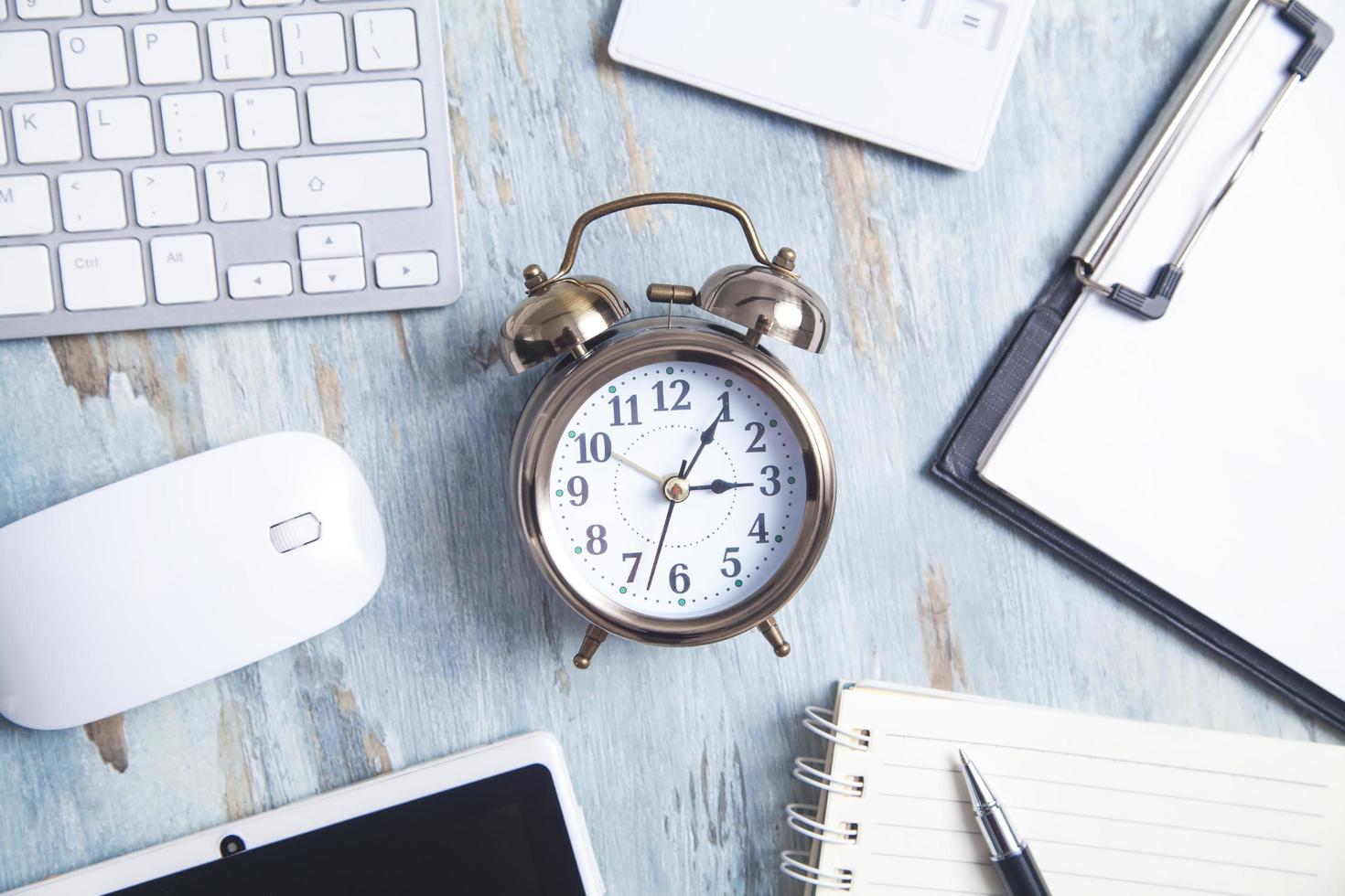 Alarm clock with business object on the desk. photo