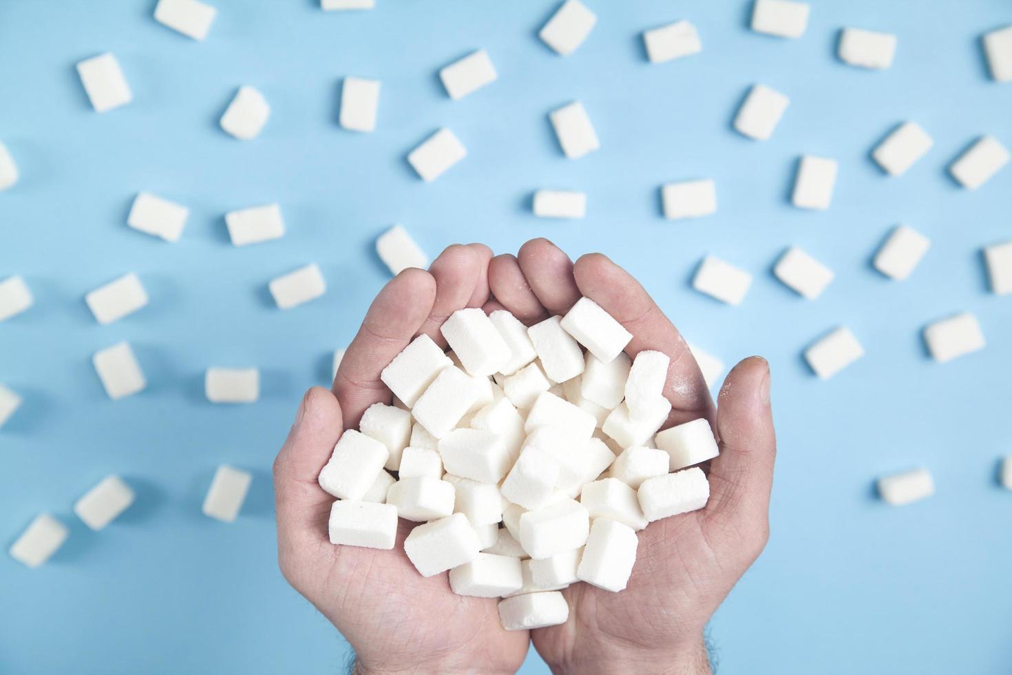 Male hands holding sugar cubes on the blue background. photo