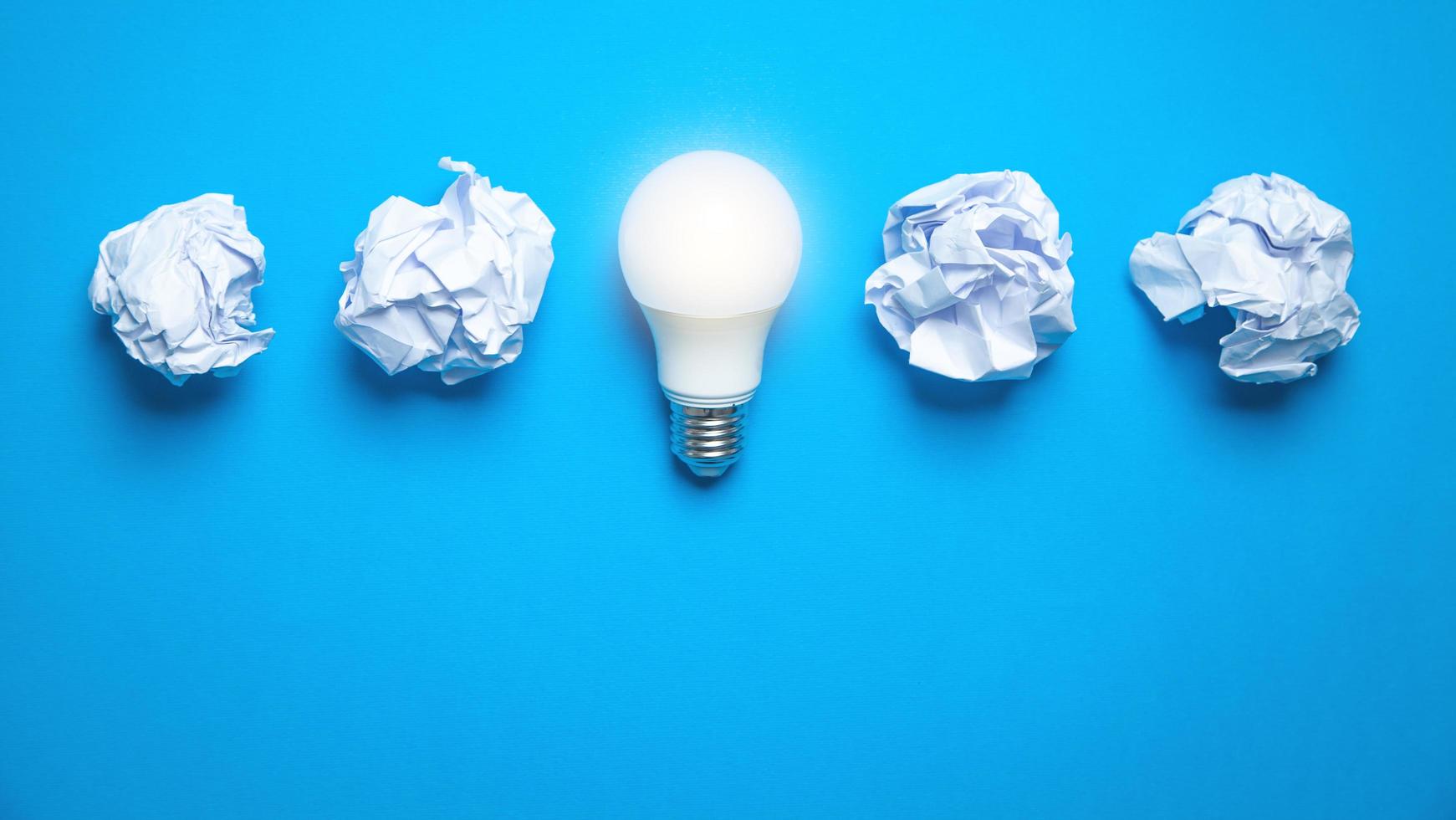 Light bulb and crumpled papers in the blue background. Idea photo