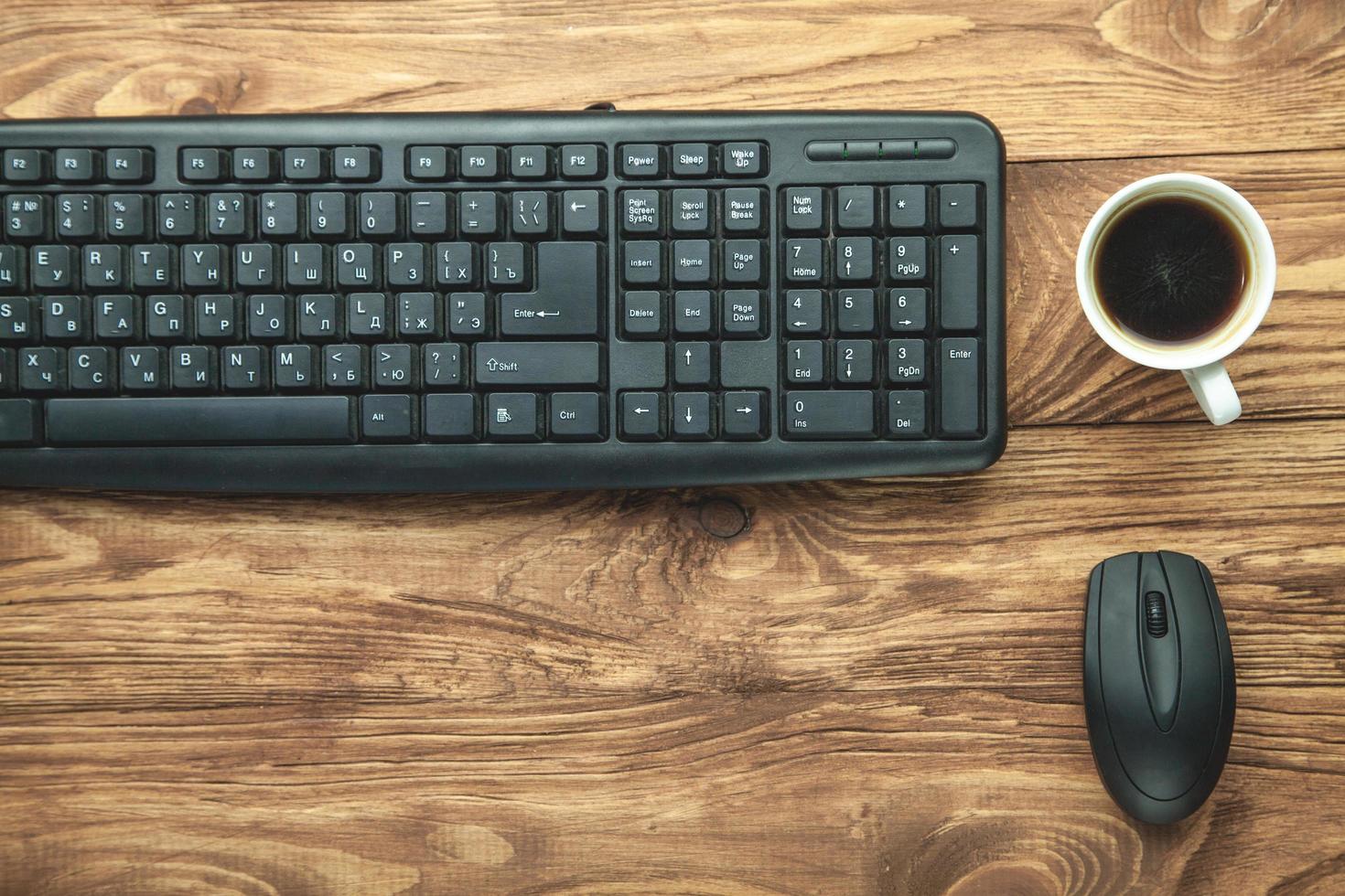 Computer keyboard and coffee on wooden desk. photo