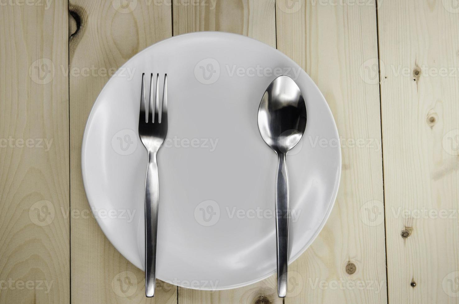 Plate and cutlery on wooden table photo