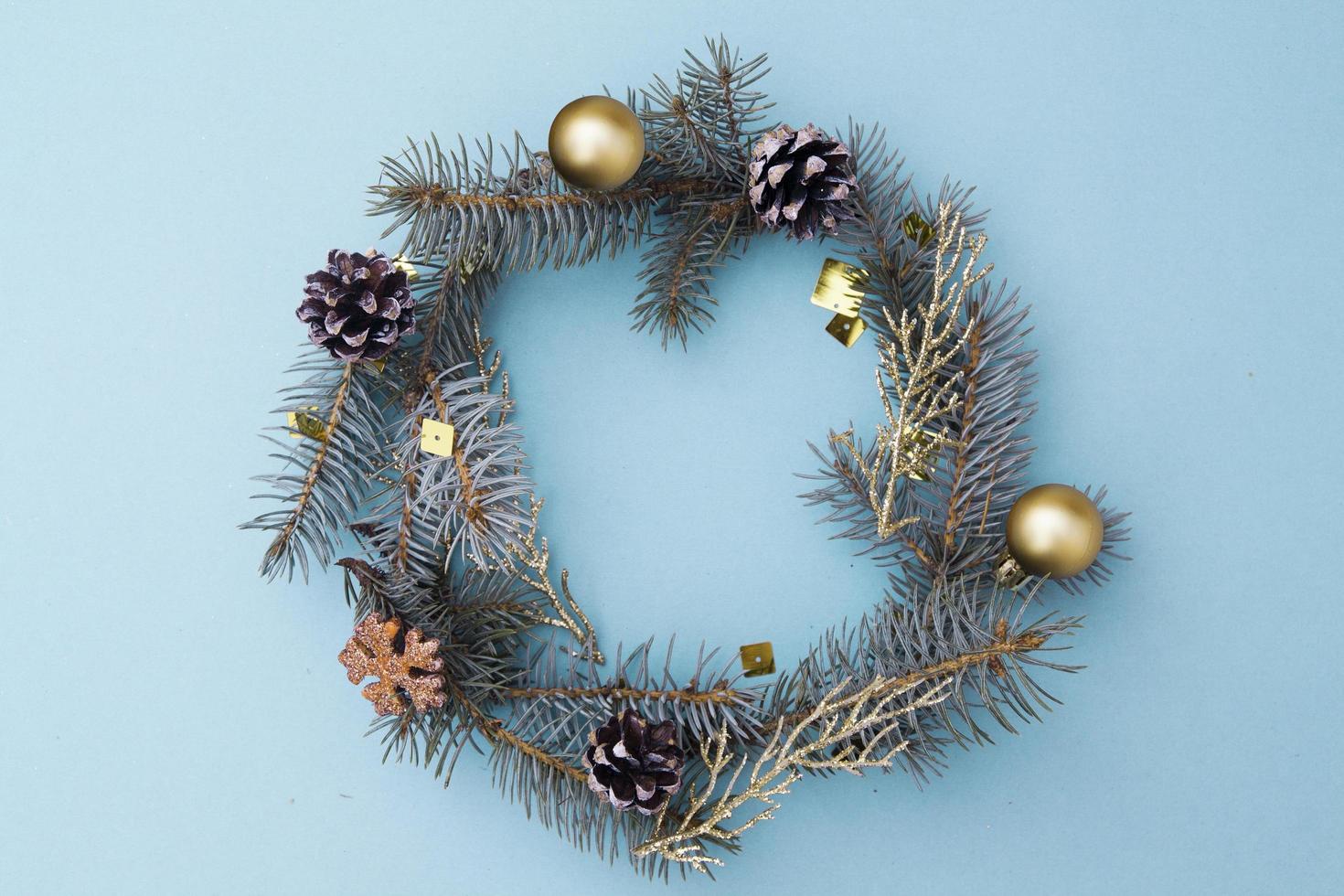 Christmas flat lay composition in the form of a wreath. Branches of blue spruce, cones, toys on a blue background. Christmas, winter, new year concept. Top view, copy space for text. photo